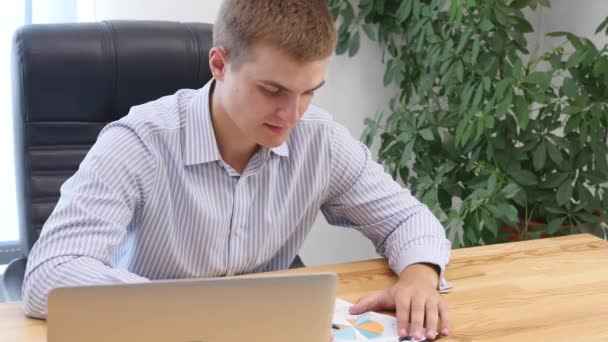De jonge zakenman leest en schrijft iets op papier aan het bureau. Sluit maar af. Begrepen, ruimte. 4k. — Stockvideo