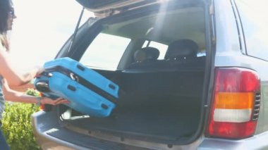 Happy man and woman put suitcases into the car boot. Close up. Copy space. 4K.