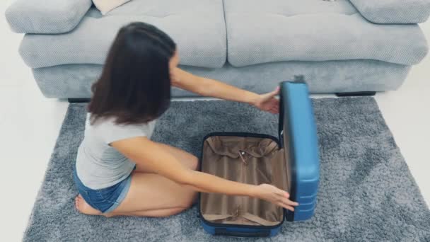 Mam is klaar voor het weekend met een enorme blauwe koffer in haar hand. Ze sluit de koffer en komt naar buiten. Bovenaanzicht. Bereid je voor op de reis. 4k. — Stockvideo