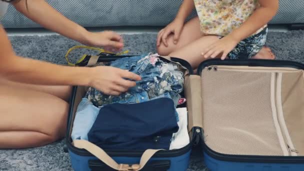 Mom is packing a huge blue suitcase. Little girl is hepling her. Getting ready for travel. Close up. 4K. — 图库视频影像