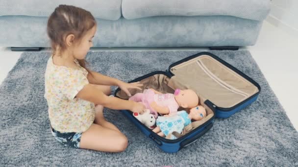 Dziecko wkłada zabawki do walizki podróżnej. Zamknij drzwi. 4k. — Wideo stockowe
