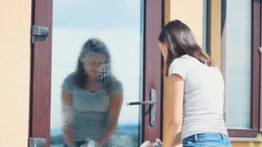 Woman is cleaning glass with a grey rag outside. Copy space. 4K.