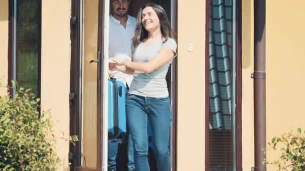 Joven pareja feliz se está preparando para ir de vacaciones. Están huyendo de la casa a un viaje impredecible. Un par se está besando. Copiar espacio. 4K . — Vídeos de Stock