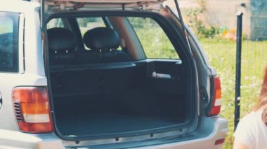 Happy man and woman put suitcases into the car boot. Close up. Copy space. 4K.