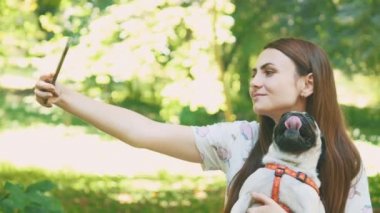 Woman is taking selfie by mobile phone with her pug dog. Close up. Copy space. 4K.