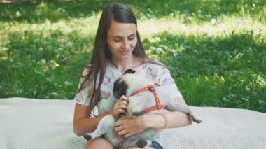 Smiling lady is taking free time with her dog. Woman relaxing in the nature with her little pug dog. Close up. Copy space. 4K.