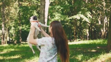 Beautiful young woman is playing with her pug dog on the park packground. Copy space. 4K.