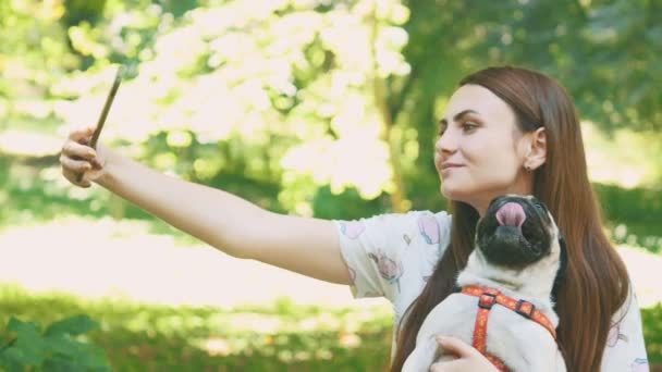 Woman is taking selfie by mobile phone with her pug dog. Close up. Copy space. 4K. — Stock video