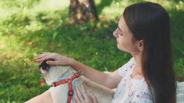 Smiling lady is taking free time with her dog. Woman relaxing in the nature with her little pug dog. Close up. Copy space. 4K.