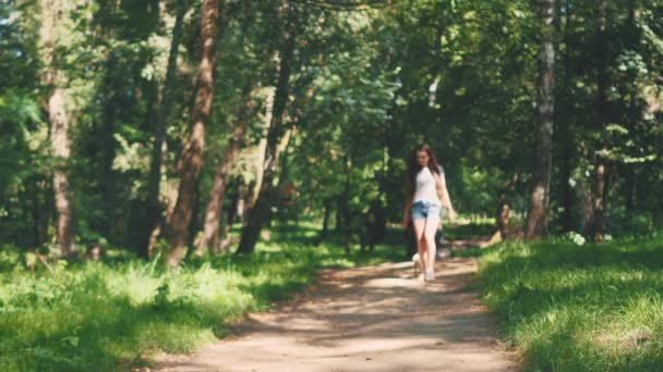 Pug dog next to a girl happily running through the path in the nature park. Copy space. 4K. — Stock Video