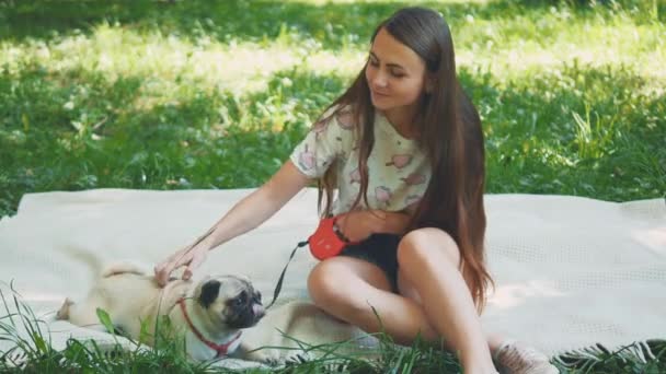 Улыбающаяся леди проводит свободное время со своей собакой. Женщина отдыхает на природе со своей маленькой собачкой-мопсом. Закрывай. Принято. 4K . — стоковое видео