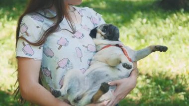 Genç kadın, köpeğini parkta sallıyor ve salıncak parkında sallanıyor. Uzayı kopyala Ekin. 4K.