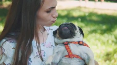 Genç kadın, köpeğini parkta sallıyor ve salıncak parkında sallanıyor. Uzayı kopyala Ekin. 4K.