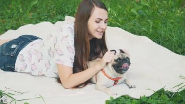 Smiling lady is taking free time with her dog. Woman relaxing in the nature with her little pug dog. Crop. Close up. Copy space. 4K.