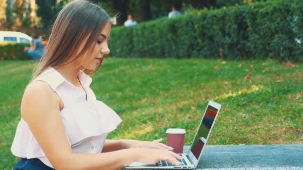 Attractive blond girl student is using laptop in city center, being inspired by nature beauty. Close up. Copy space. 4K. — ストック動画