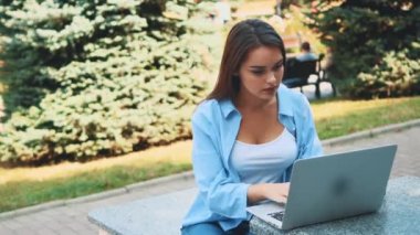 Attractive brunette girl student is using laptop in city center, being inspired by nature beauty. Close up. Copy space. 4K.