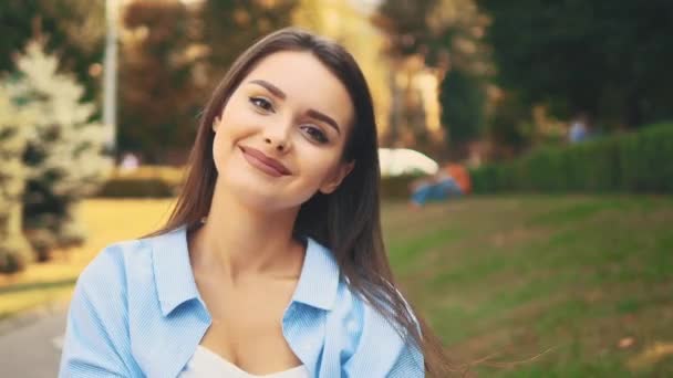 Menina feliz sorri sinceramente, estando no fundo turvo do parque de verão. Fecha. Espaço para cópia. 4K . — Vídeo de Stock