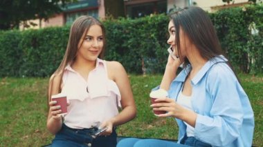 The girl after shopping sits in the park on the bench and one of the is on the phone, while another is sitting next to her. Close up. Copy space. 4K