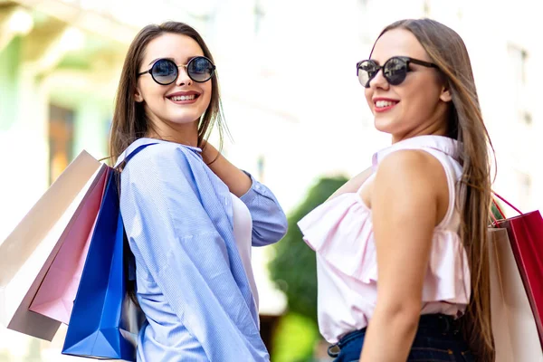 Smiling traveling girls on the streets of another country with shopping bags, enjoying season of discounts. — 스톡 사진