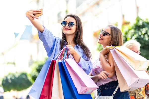 Las mujeres inspiradas están utilizando el teléfono inteligente vlogging su día de compras en el fondo borroso de la ciudad . — Foto de Stock