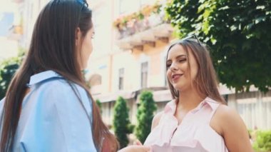 İki çekici genç kadın bir yaz caddesinde konuşuyor. Kapatın. Uzayı kopyala 4K