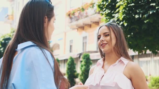 Deux jolies jeunes femmes parlent dans une rue d'été. Ferme là. Espace de copie. 4K — Video