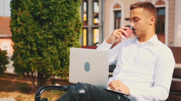 Empresario, con estilo de negocios y mecanografía en el ordenador portátil mientras está sentado al aire libre en el parque en el banco. De cerca. Copiar espacio. 4K . — Vídeos de Stock