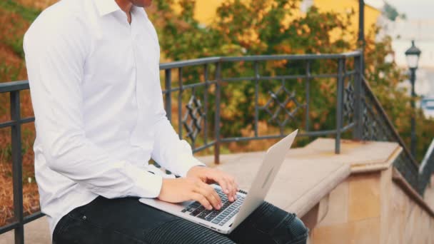 Felismerhetetlen férfi, üzleti stílust visel és gépel a laptop számítógépén, miközben kint ül a parkban a lépcsőn. Közelről. Másold a helyet. 4K. — Stock videók