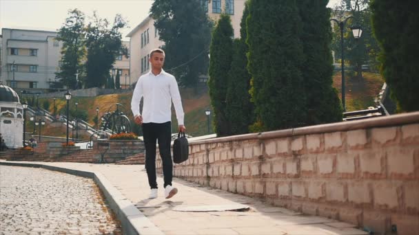 Un joven hombre de negocios guapo con una camisa blanca camina por las calles. Lento. En cámara lenta. De cerca. Copiar espacio. 4K . — Vídeos de Stock