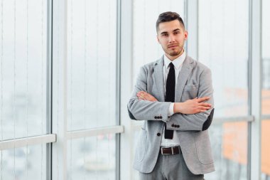 Kendine güvenen genç işadamı elleri bağlı, kameraya bakıyor, sıkı çalışmaya hazır..