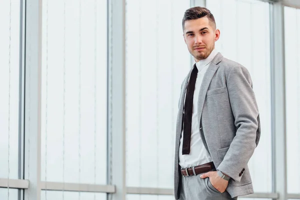 Trabalhador de escritório casual masculino sorrindo no escritório, de pé, mantendo a mão no bolso, olhando encantado . — Fotografia de Stock