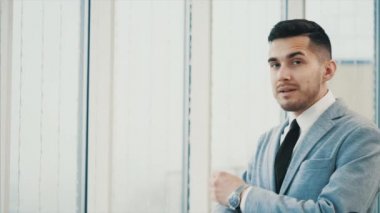 İş adamı gülümsüyor, kameraya bakıyor, beyaz bulanık arka planda soyutlanmış. Kapatın. Uzayı kopyala 4K.