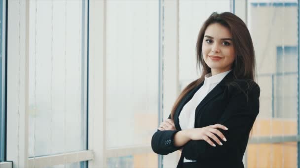 Mujer de negocios sonriendo para la cámara con las manos cruzadas o dobladas mientras posa, aislada sobre fondo panorámico blanco. De cerca. Copiar espacio. 4K . — Vídeo de stock