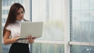 Business woman is working with a grey laptop, isolated on light panoramic blurred background. Copy space. Close up. 4K.