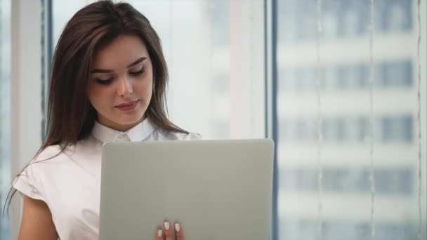 Business woman is working with a grey laptop, isolated on light panoramic blurred background. Copy space. Close up. 4K. — ストック動画