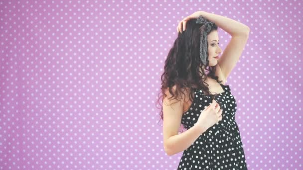Kinky morena menina no vestido polka-dot preto agradável reajustando seu penteado . — Vídeo de Stock