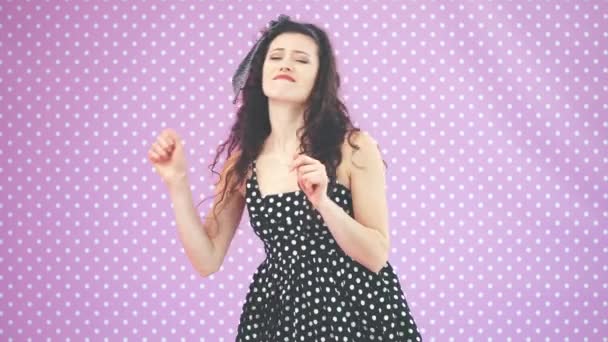 Schönes junges Mädchen mit verworrenem Haar, in schwarzen Tupfen tanzend und witzig mit den Händen winkend. — Stockvideo