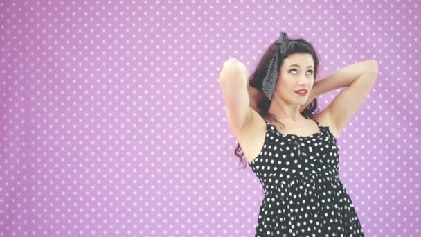 Perverzní brunnete dívka v pěkné černé polka-dot šaty upravující její účes, příjemně se usmívá. — Stock video