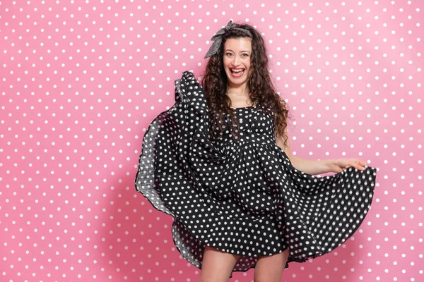 Pinup curly girl is making windy dress, posing, grinning at the camera. — Stock Photo, Image