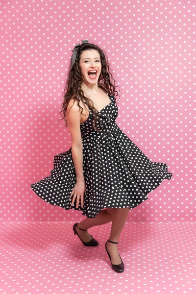 Energetische sexy Mädchen in Pin-up-Stil dreht sich um, lächelt fröhlich und posiert in die Kamera, macht windige Kleid. — Stockfoto