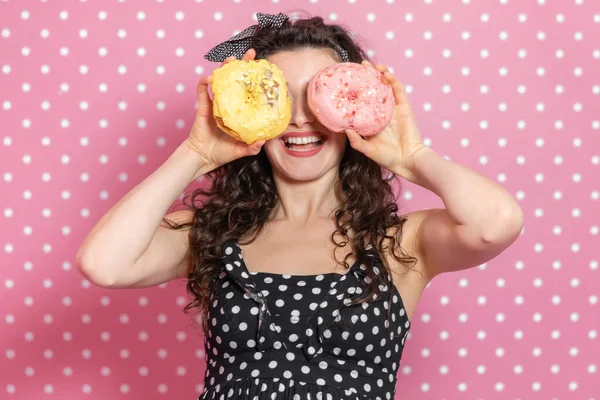 Heureuse jeune femme regarde à travers deux beignets comme par binoculaire et souriant agréablement . — Photo
