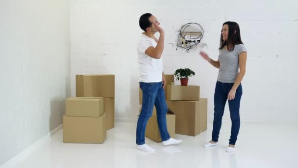 Glückliches Paar trägt Kartons bei sich und plant das Interieur ihres neuen Hauses. — Stockvideo