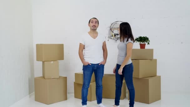 Glückliches Paar trägt Kartons bei sich und plant das Interieur ihres neuen Hauses. — Stockvideo