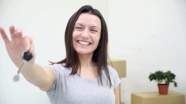 Dişi dişli kadın daire sahibi ya da kiracı kameranın anahtarlarını gösterirken kocası arka planda bulanık kutular taşıyor..