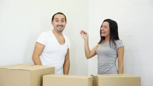Зубчатая кавказская пара появляется из-за коробок и показывает ключи от своей новой квартиры на камеру . — стоковое видео