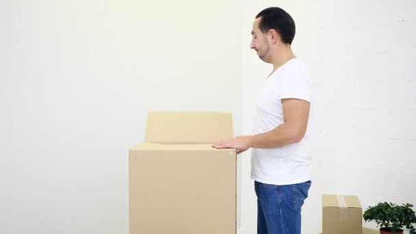 Young satisfied bachelor man upacking carton box, pulling out clothes and throwing them everywhere with great excitement. — Stock Video