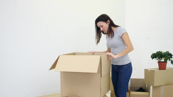 Quelques boîtes de carton de déballage après avoir déménagé dans une nouvelle maison et ne peut pas trouver certains effets personnels, l'air irrité . — Video