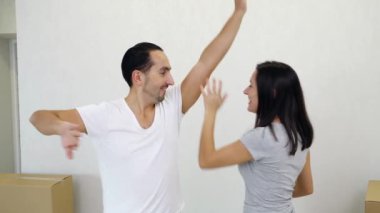Sevecen genç aile yeni evlerinde karton kutuların arasında dans edip eğleniyorlar..