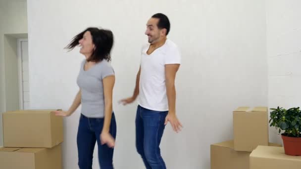 Pareja se divierte bailando cómicamente y riendo en su nuevo apartamento . — Vídeos de Stock