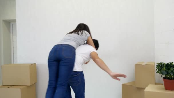 Doce casal jogando piggyback, se divertindo em seu novo apartamento . — Vídeo de Stock